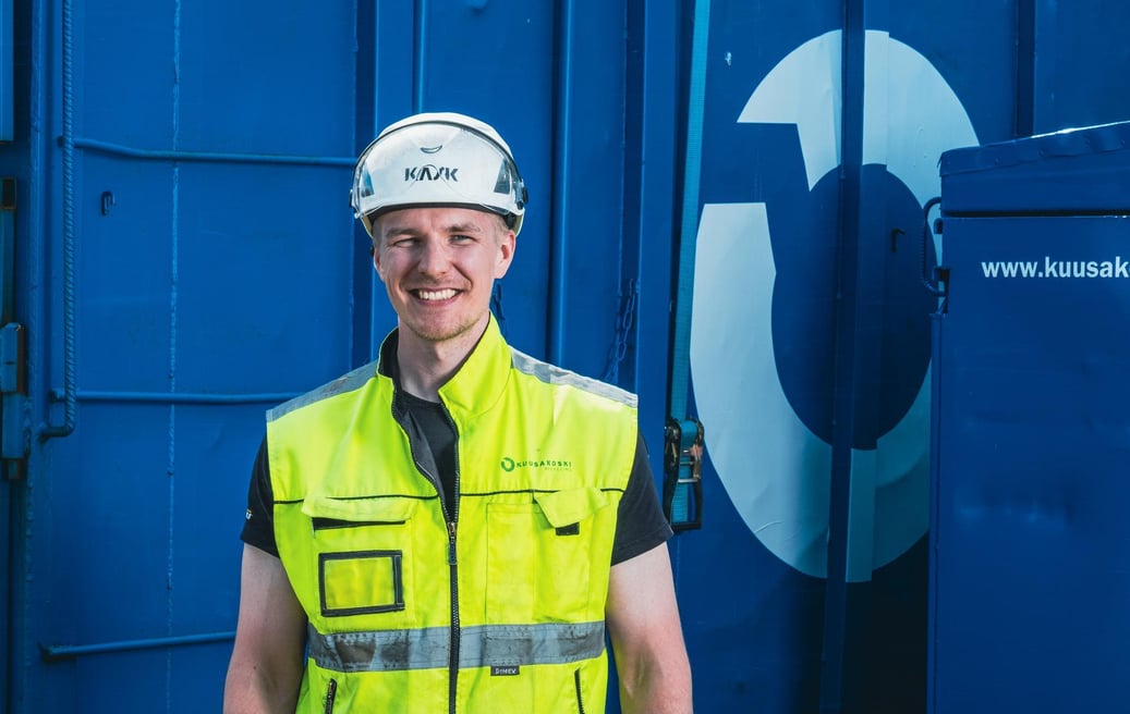 An_Kuusakoski_employee_in_front_of_the_container_smiling_customer_portal_project_with_Zure