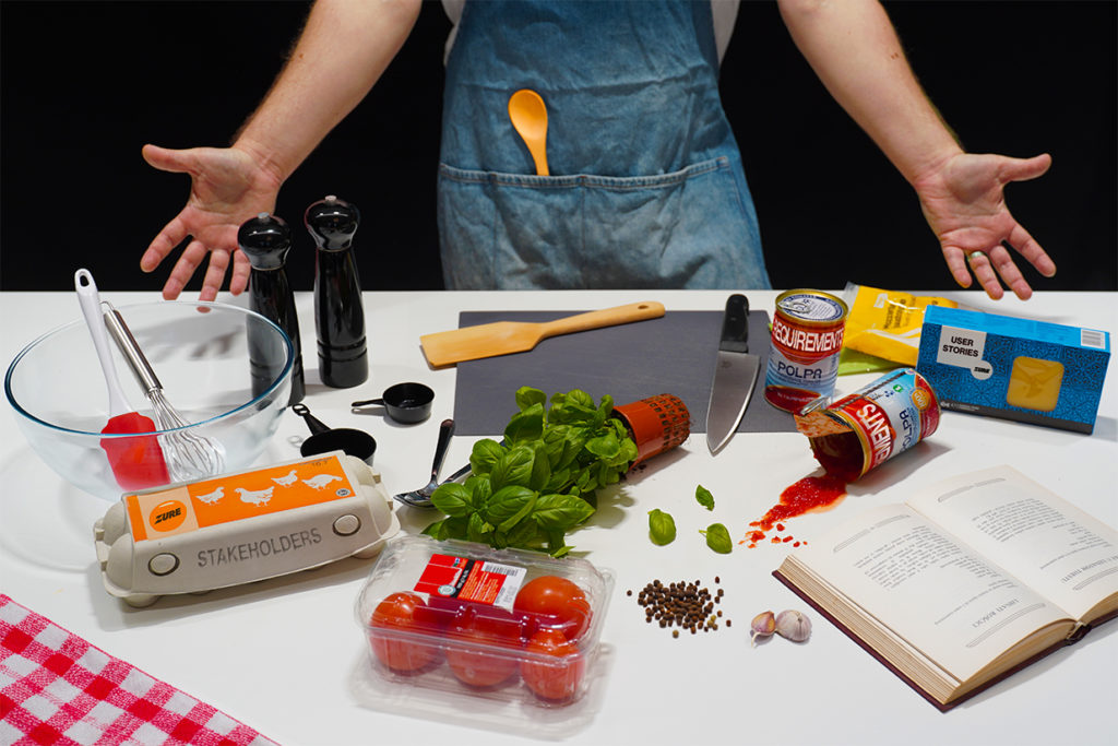 A cooking setup with ingredients such as basil, tomatoes, stakeholders, user stories and requirements in a can. Replacing old system with a new one.